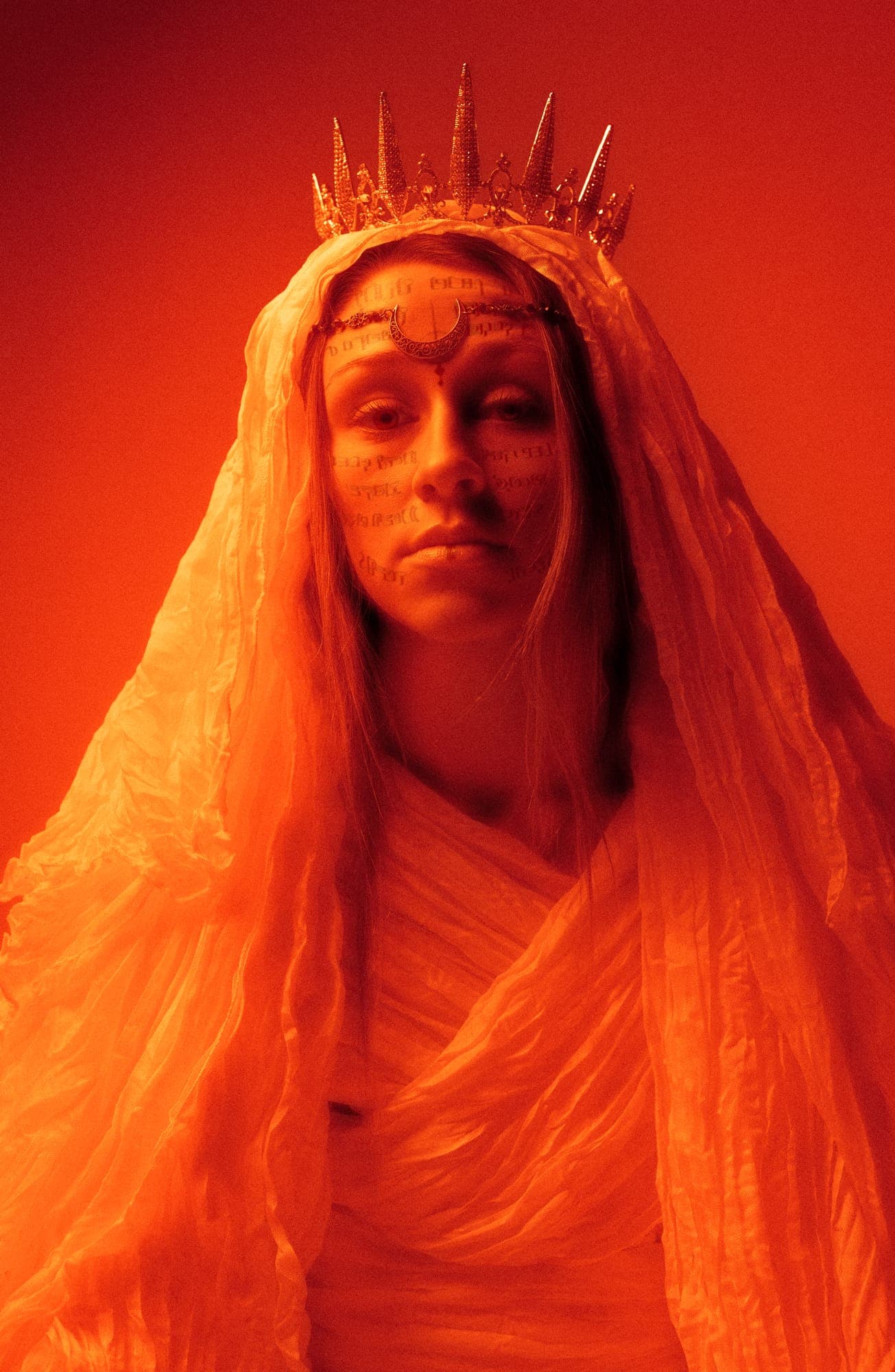 crowned figure in a white veil, bathed in red light